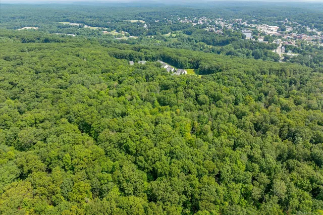 an aerial view of residential house with outdoor space and trees all around
