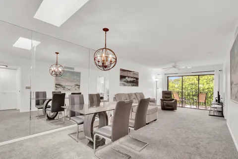 a view of a dining room and livingroom with furniture large windows and a chandelier