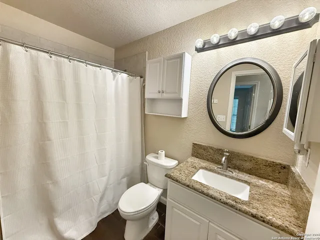 a bathroom with a granite countertop sink mirror vanity and a toilet