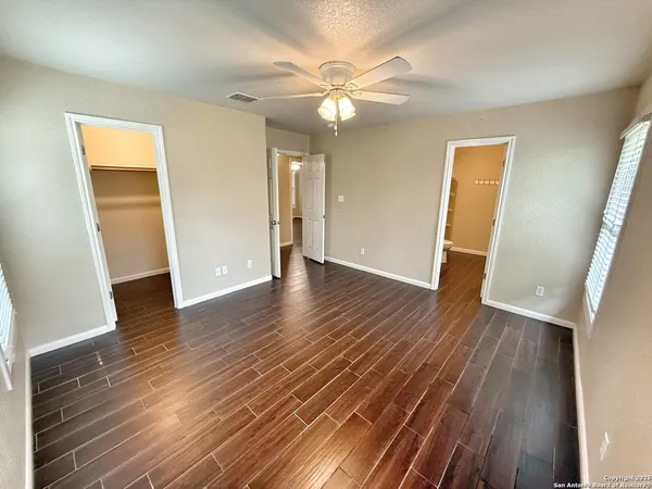 an empty room with wooden floor and a ceiling fan