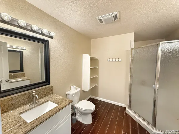 a bathroom with a granite countertop sink toilet and shower