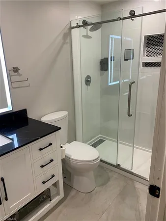 a bathroom with a granite countertop sink toilet and shower