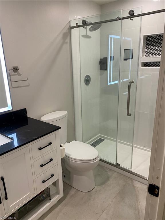 5717 Lago Villaggio Way Naples, FL 34104 - Photo 2 of 11 a bathroom with a granite countertop sink toilet and shower