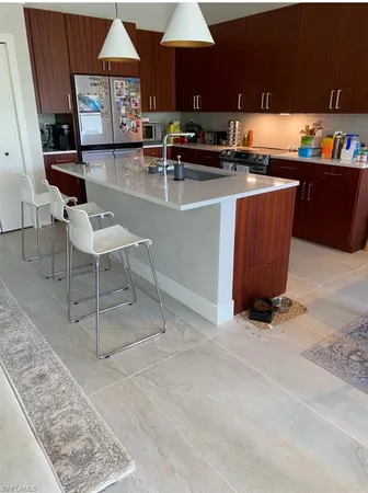 a kitchen with stainless steel appliances kitchen island granite countertop a table chairs sink and cabinets