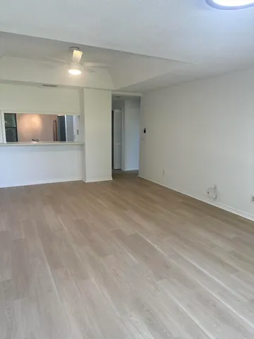 a view of an empty room with window and wooden floor