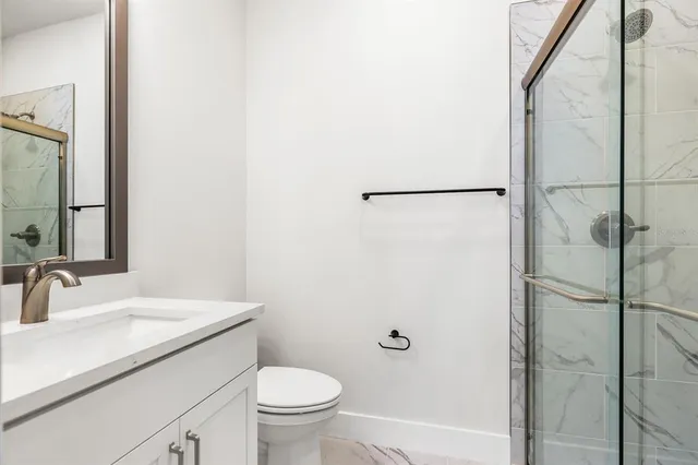 a kitchen with stainless steel appliances granite countertop a refrigerator a sink dishwasher a stove and white cabinets with wooden floor