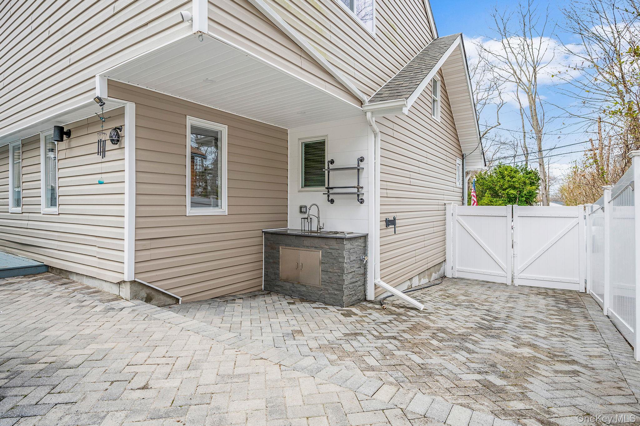 38 Hawthorne Road Rocky Point, NY 11778 - Photo 6 of 27 a view of a white house with a yard and lawn chairs under an umbrella