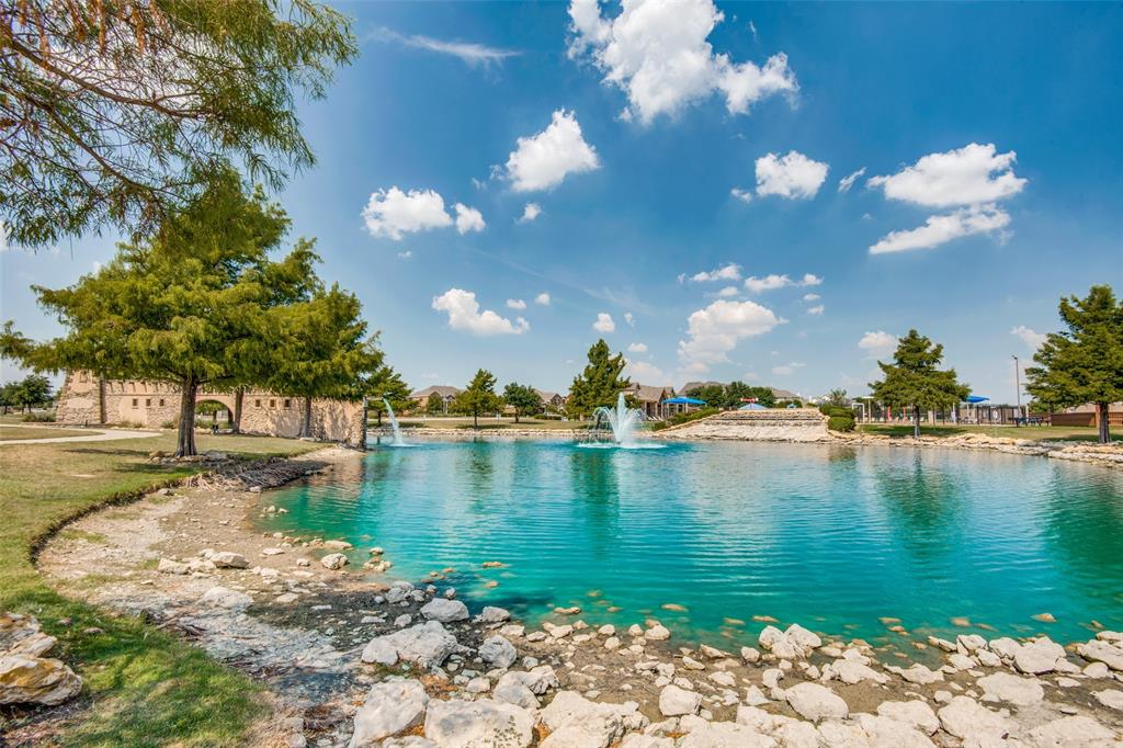 1257 Barrel Run Fort Worth, TX 76052 - Photo 26 of 26 Expansive blue-hued pond featuring two water fountains, bordered by a rocky shoreline and green lawn