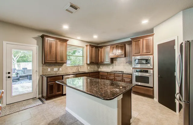 a kitchen with stainless steel appliances granite countertop a refrigerator a stove a sink and a microwave