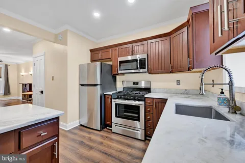 a kitchen with stainless steel appliances granite countertop a stove a sink dishwasher a refrigerator and a microwave oven with wooden floor