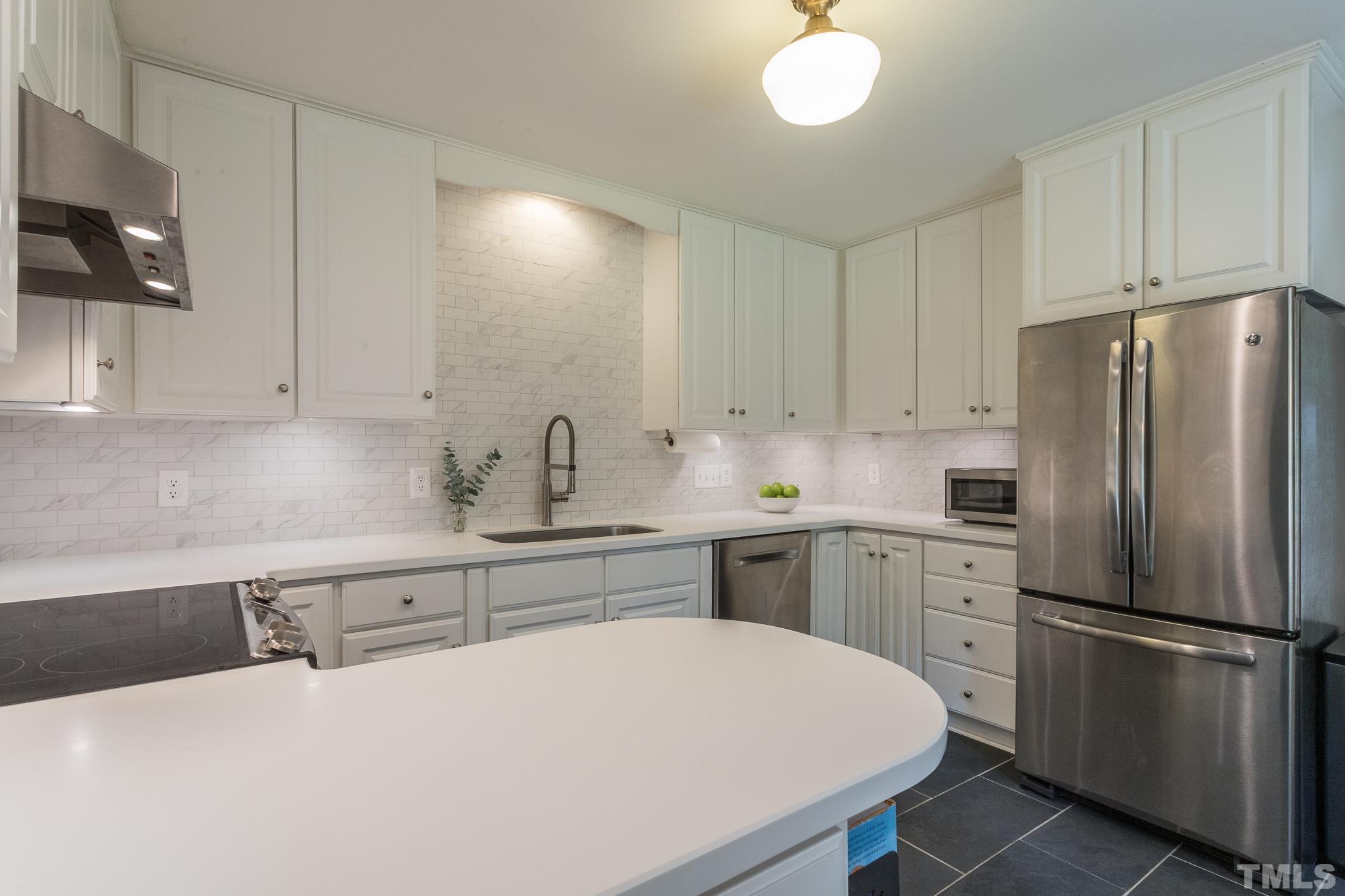 3431 Churchill Road Raleigh, NC 27607 - Photo 31 of 47 a kitchen with a refrigerator a sink a stove and white cabinets