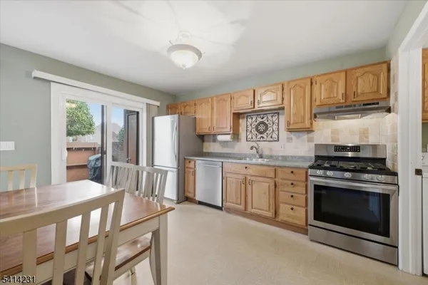 a kitchen with stainless steel appliances granite countertop a stove a sink dishwasher a refrigerator and cabinets with wooden floor