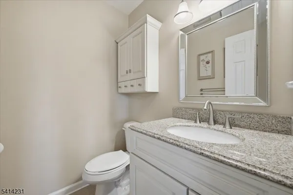 a bathroom with a granite countertop toilet a sink and a mirror