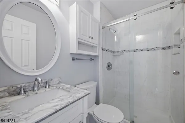 a bathroom with a granite countertop sink toilet a mirror and shower