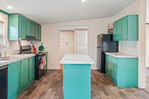 a kitchen with kitchen island a sink stove and refrigerator