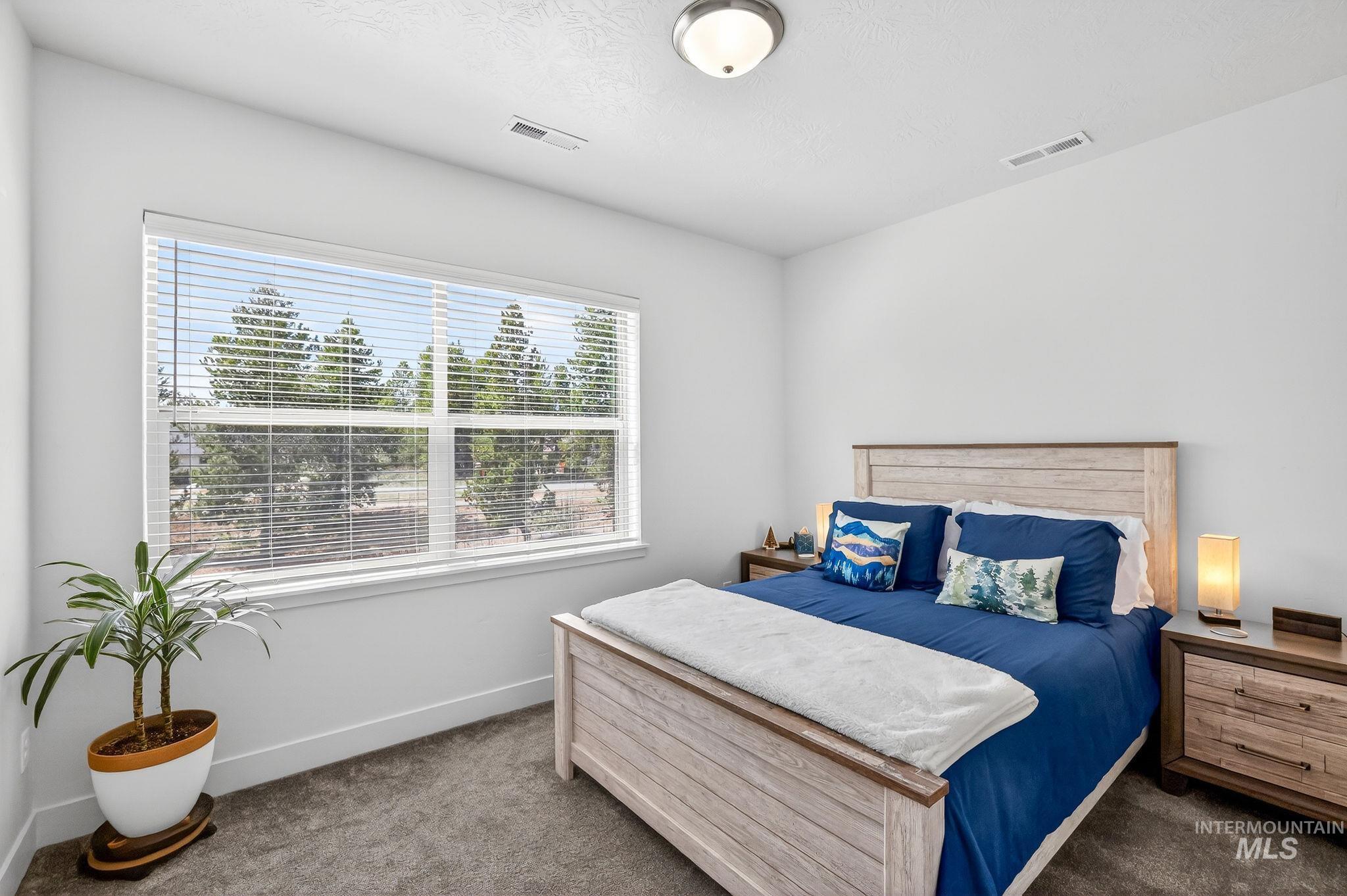 311 Broken Ridge Way McCall, ID 83638 - Photo 19 of 44 Bedroom featuring a large window, neutral wall paint, ceiling-mounted light fixture, and plush carpet flooring