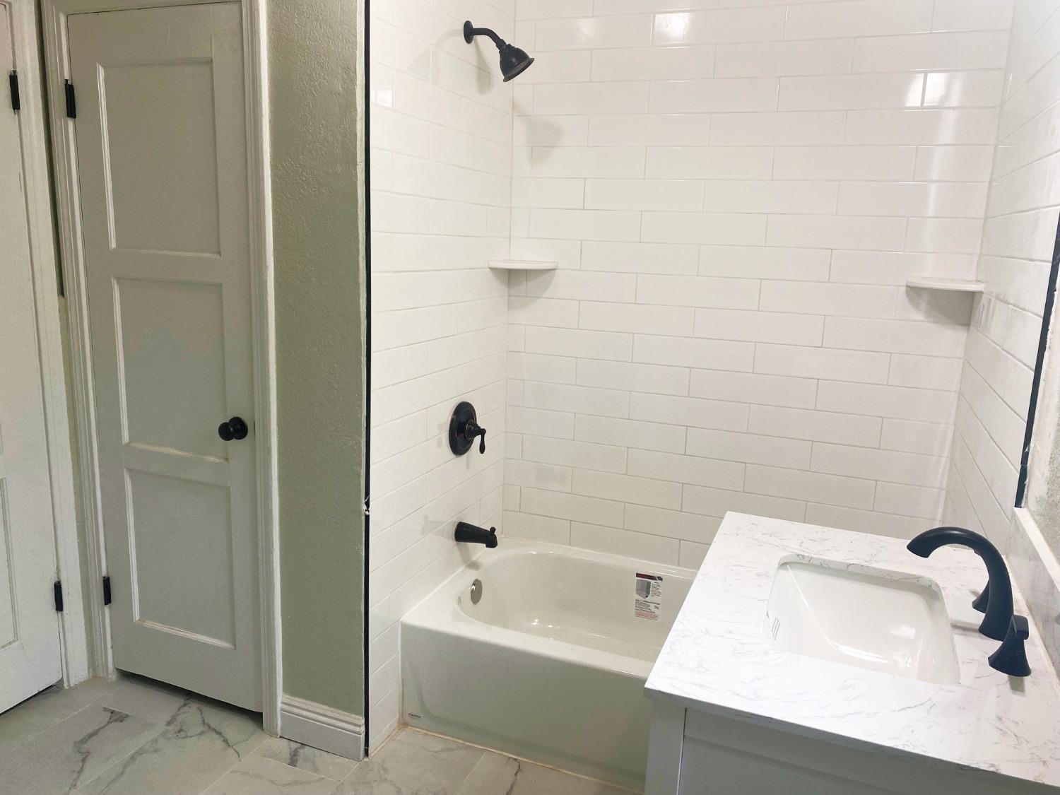 931 F Street Reedley, CA 93654 - Photo 8 of 11 a bathroom with a sink a shower and a bathtub