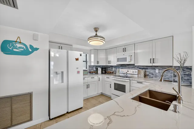 a kitchen with stainless steel appliances granite countertop a refrigerator a stove a sink dishwasher and white cabinets with wooden floor