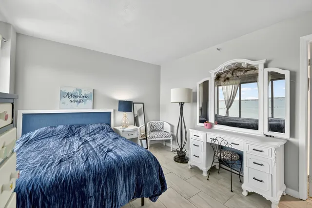 a spacious bedroom with a bed a mirror on dresser and a chandelier