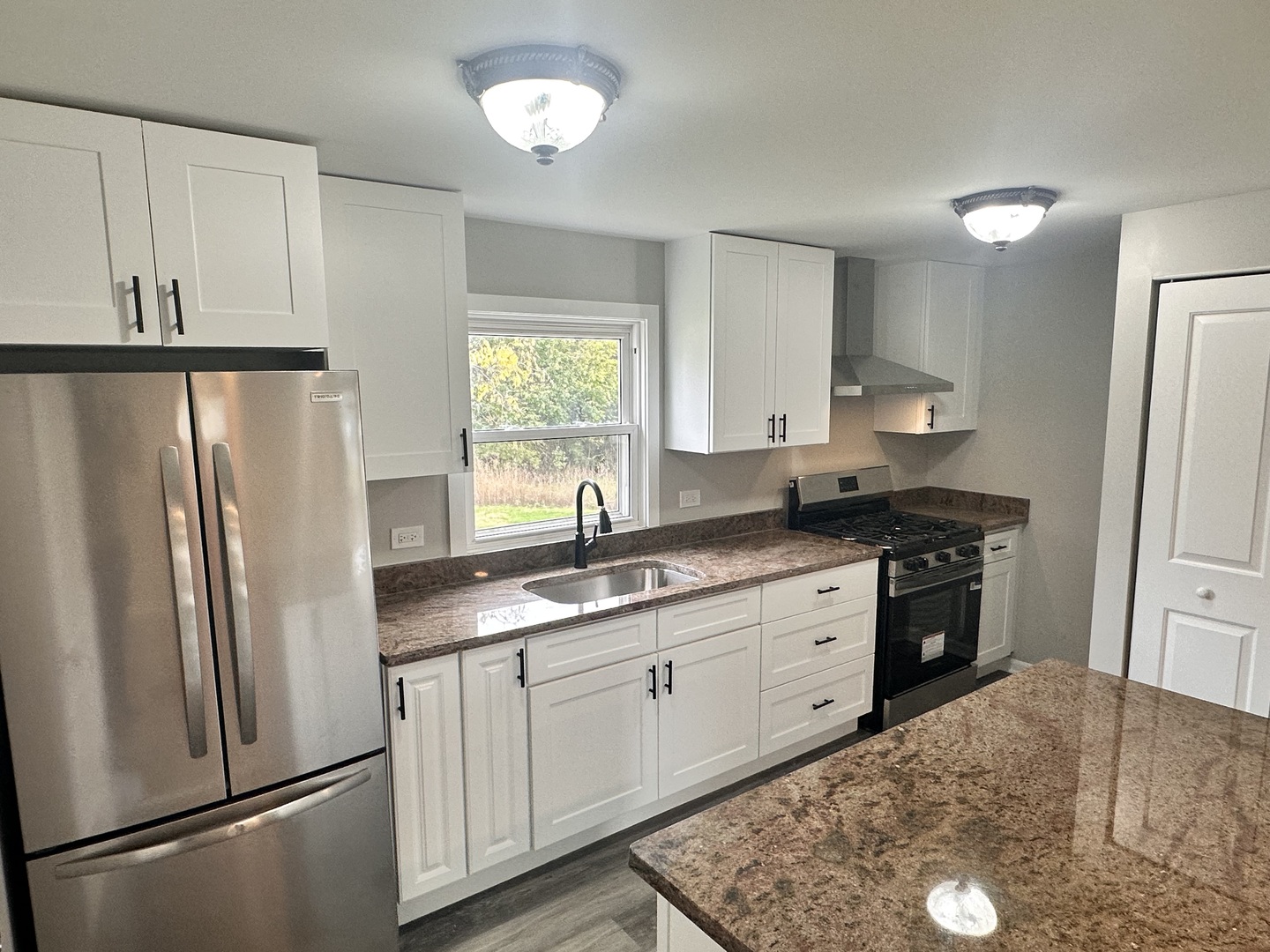 248 North State Street Franklin Grove, IL 61031 - Photo 12 of 26 a kitchen with stainless steel appliances granite countertop a refrigerator a stove a sink and white cabinets