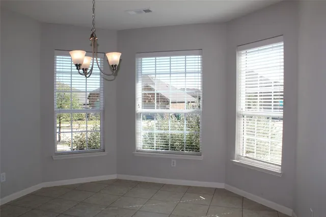 a view of an empty room with a window and chandelier