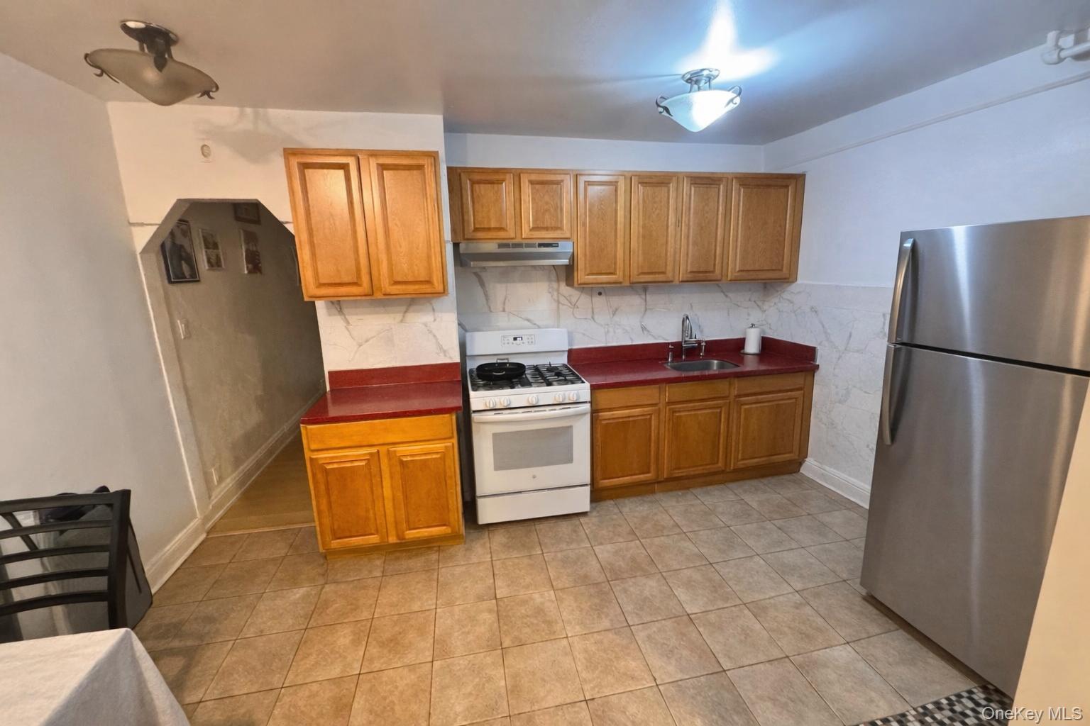86-75 80th Street Queens, NY 11421 - Photo 16 of 29 a kitchen with granite countertop a refrigerator a sink a stove a washer dryer and cabinets