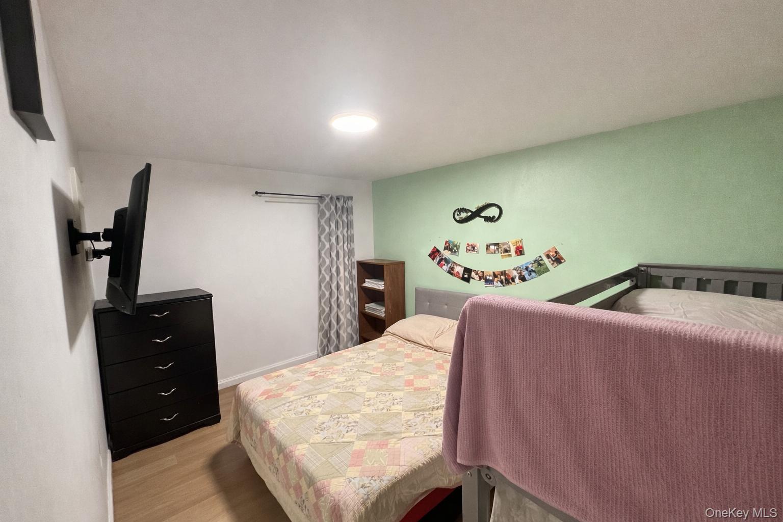 86-75 80th Street Queens, NY 11421 - Photo 21 of 29 a bedroom with a bed and a flat tv screen on dresser