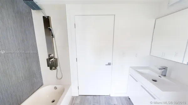 a bathroom with a tub sink a mirror and shower