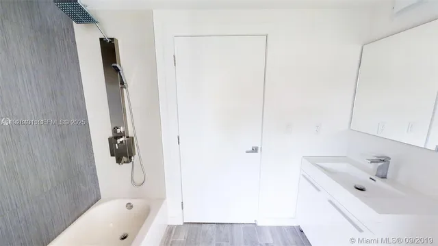 a bathroom with a tub sink a mirror and shower
