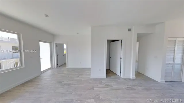 a view of an empty room with window and bathroom