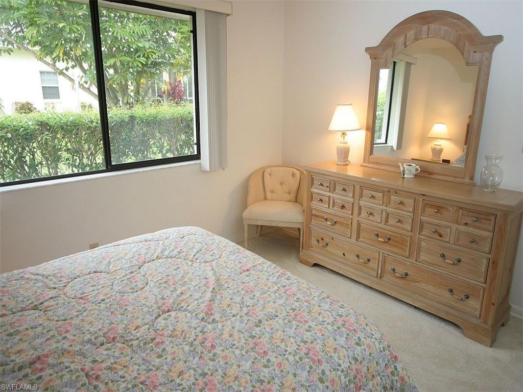 1961 Imperial Golf Course Boulevard Naples, FL 34110 - Photo 12 of 13 a bedroom with a bed a mirror on dresser and a large window