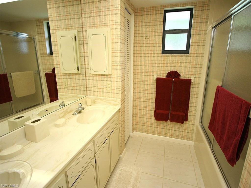 1961 Imperial Golf Course Boulevard Naples, FL 34110 - Photo 13 of 13 a bathroom with a tub sink and mirror