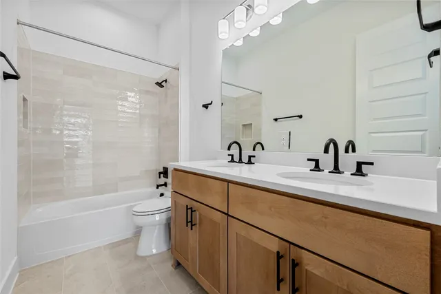 a bathroom with a double vanity sink a toilet a mirror and shower