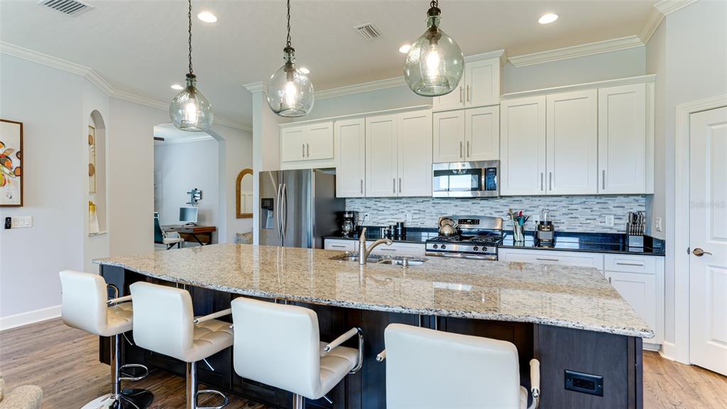 4511 Terrazza Court Lakewood Ranch, FL 34211 - Photo 11 of 65 a kitchen with stainless steel appliances granite countertop a sink a refrigerator a stove a dining table and chairs