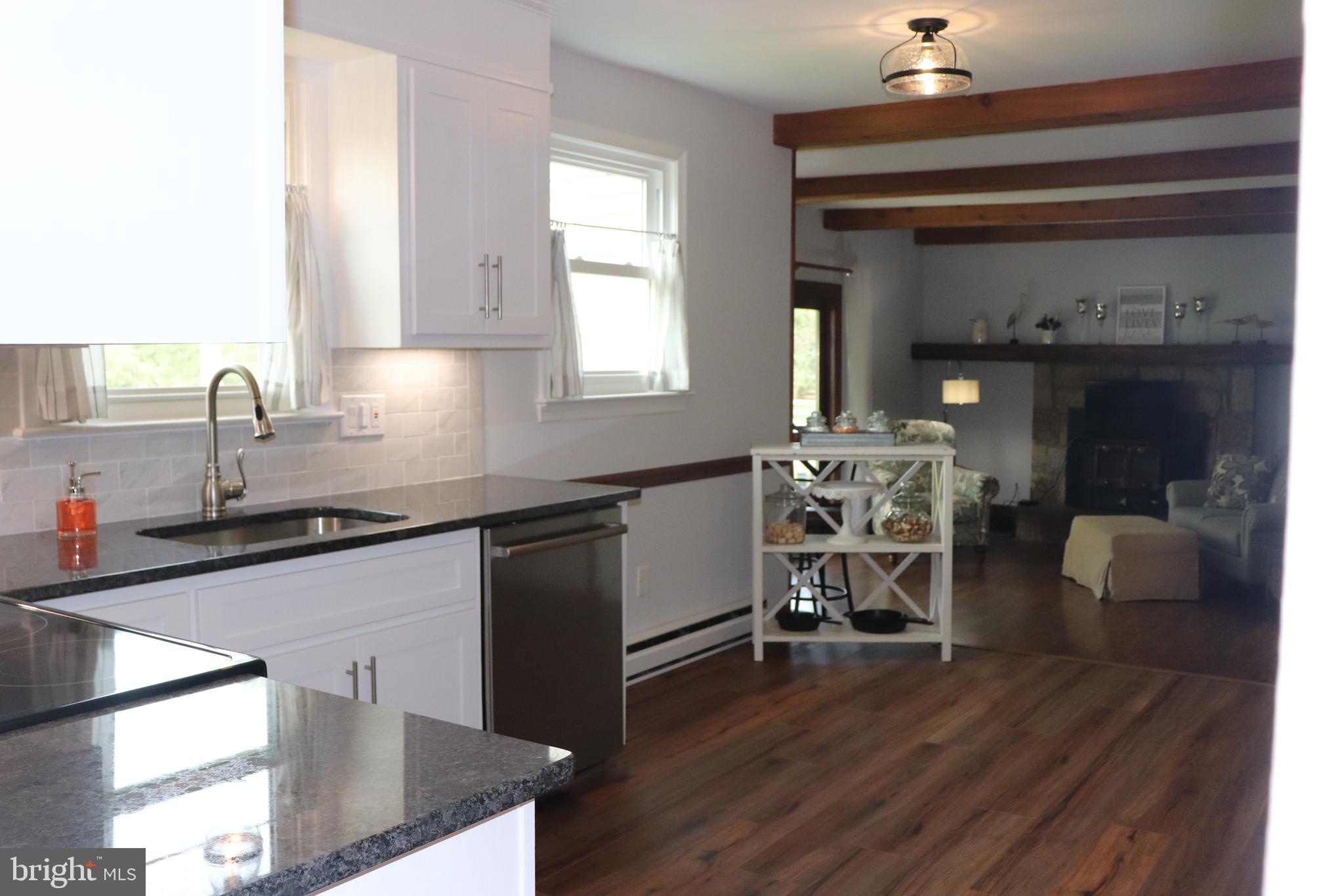 2181 School Road Pottstown, PA 19465 - Photo 9 of 42 a kitchen with stainless steel appliances granite countertop a sink dishwasher a stove cabinets and a dining table with wooden floor