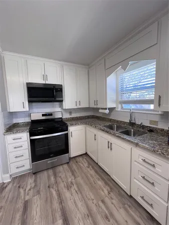 a kitchen with granite countertop a stove a sink and a microwave
