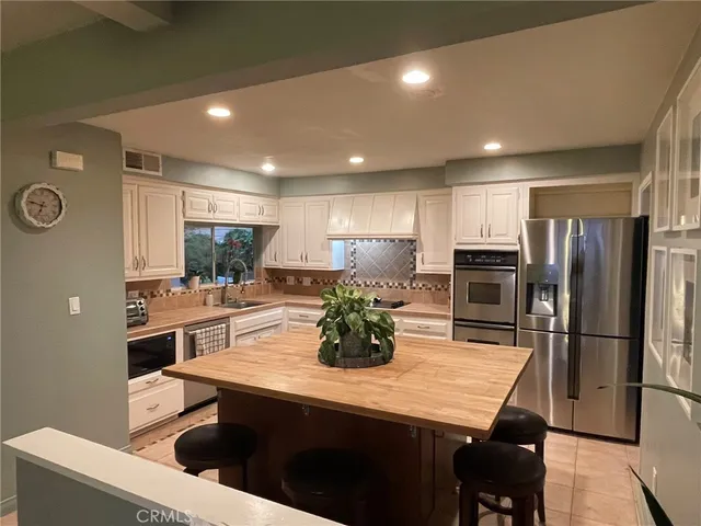 a kitchen with kitchen island a refrigerator stove microwave and cabinets
