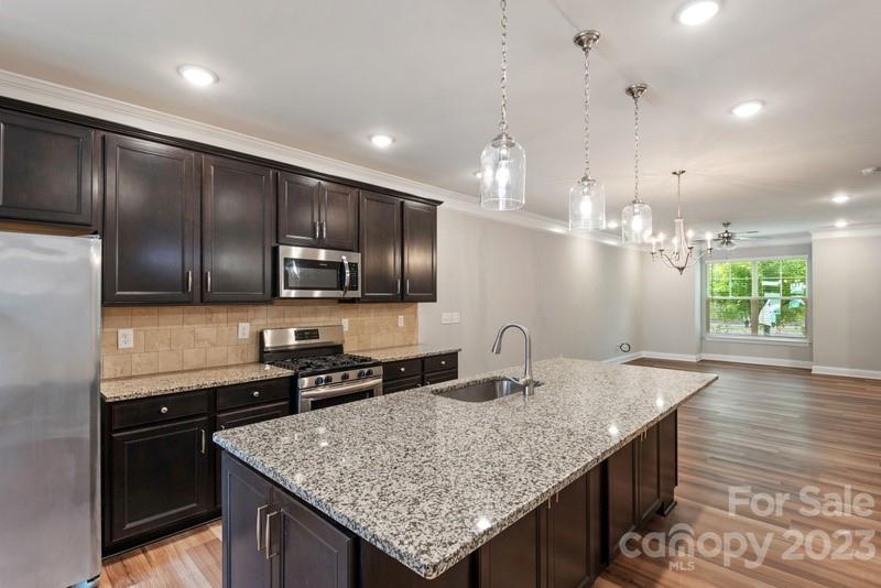 a kitchen with granite countertop kitchen island stainless steel appliances a sink stove and refrigerator