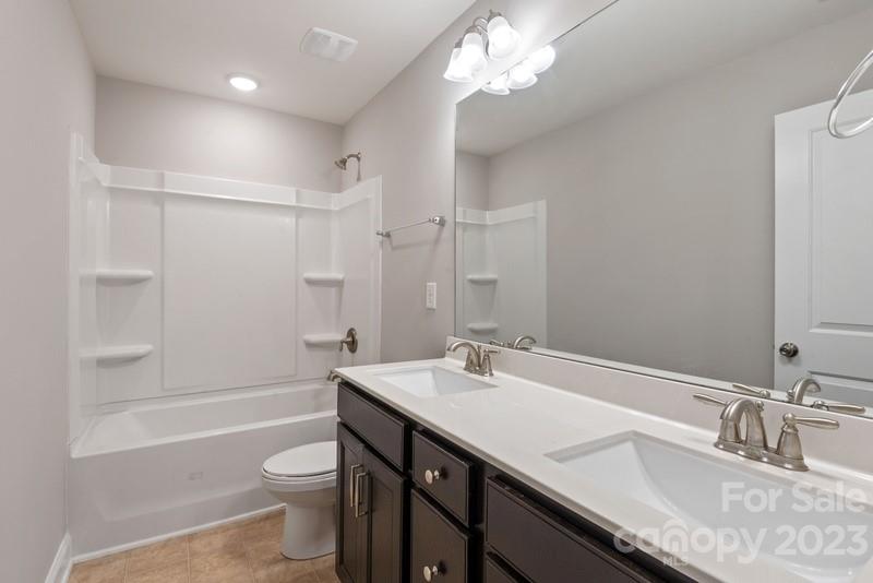 208 Waterlynn Ridge Road, Unit D Mooresville, NC 28117 - Photo 17 of 23 a bathroom with a granite countertop sink a toilet a mirror and shower
