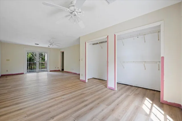 an empty room with wooden floor cabinet and windows
