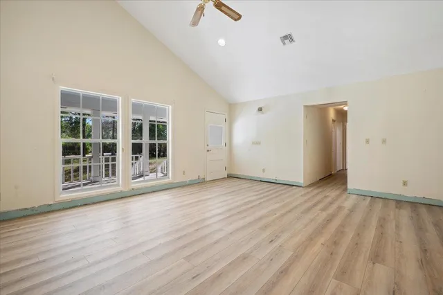 an empty room with wooden floor and windows