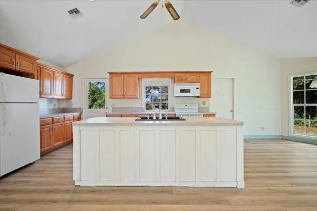 a kitchen with kitchen island granite countertop white cabinets and wooden floor