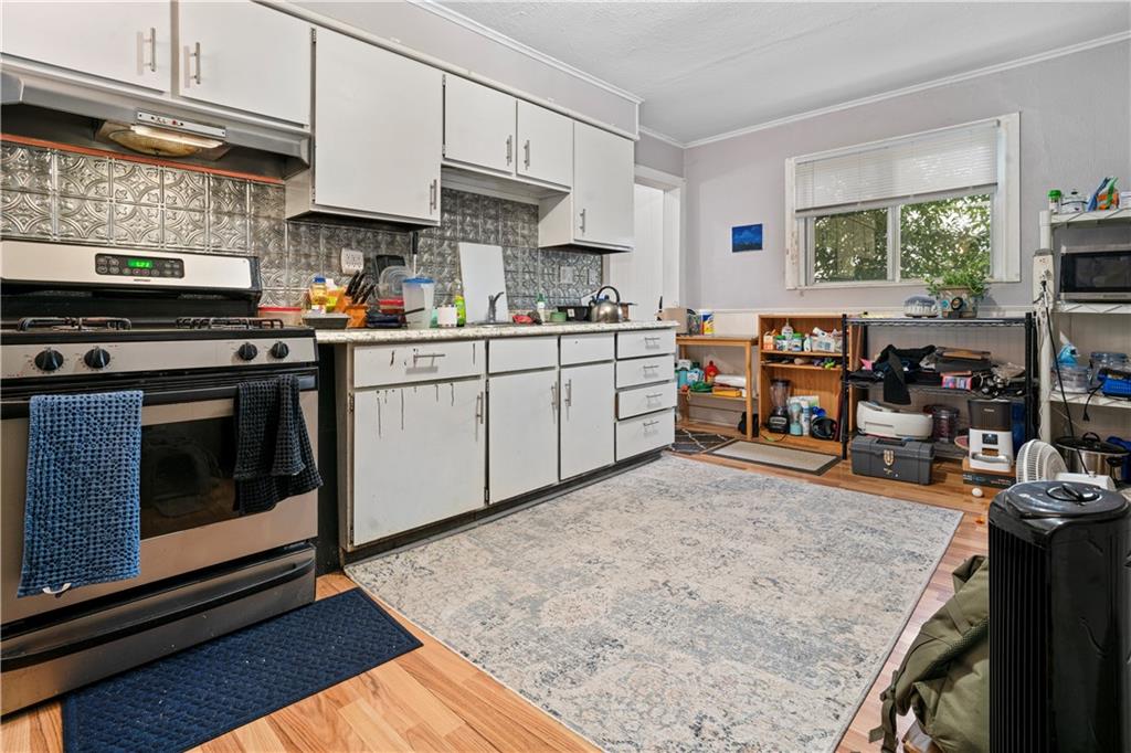 7709 Juniata Street Pittsburgh, PA 15218 - Photo 9 of 22 a kitchen with stainless steel appliances granite countertop a stove top oven a sink a dining table and chairs with wooden floor