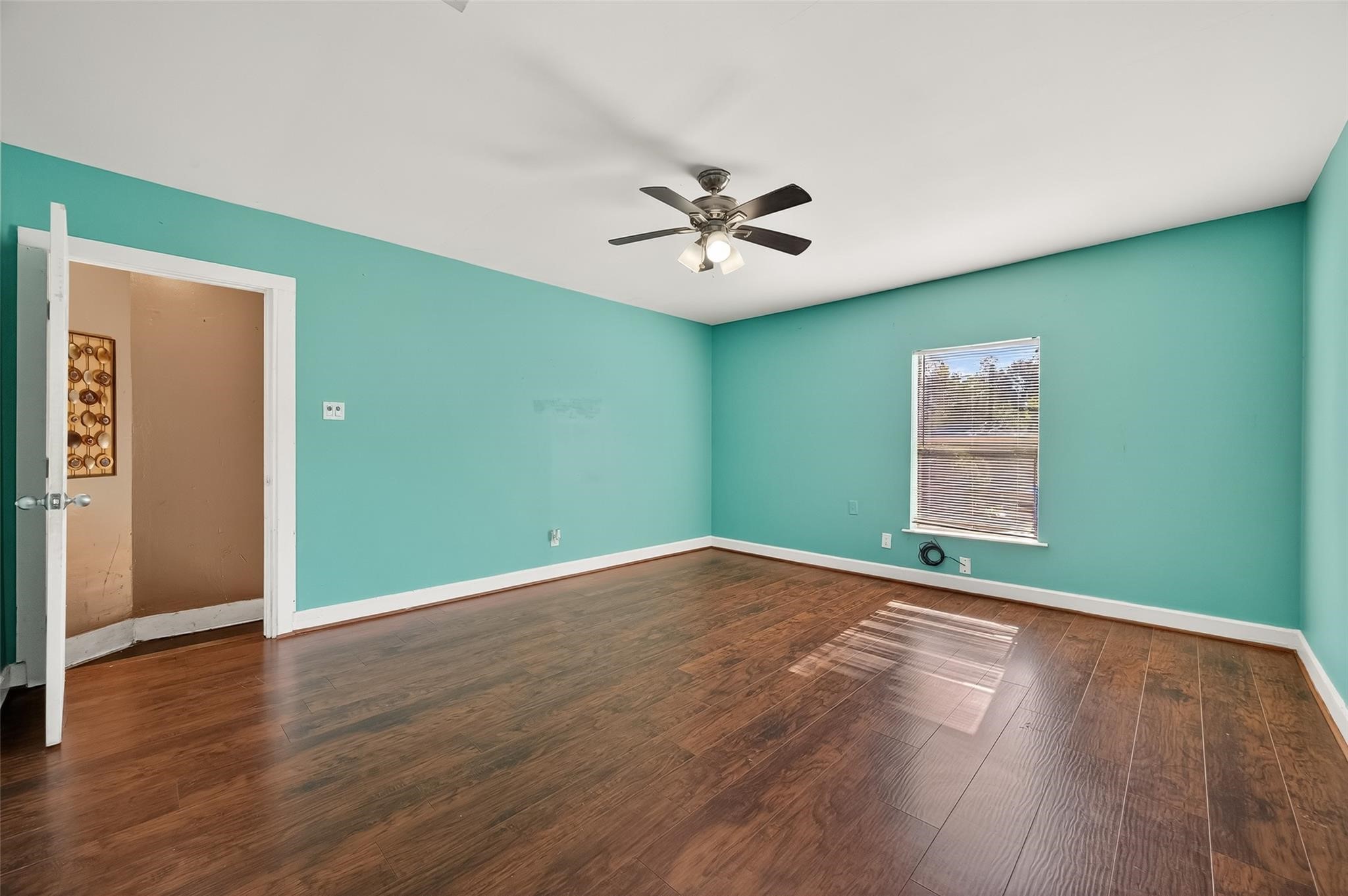 7111 Myrtle Street Houston, TX 77087 - Photo 5 of 24 an empty room with wooden floor chandelier fan and windows
