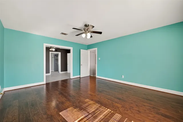 a view of an empty room with window and wooden floor