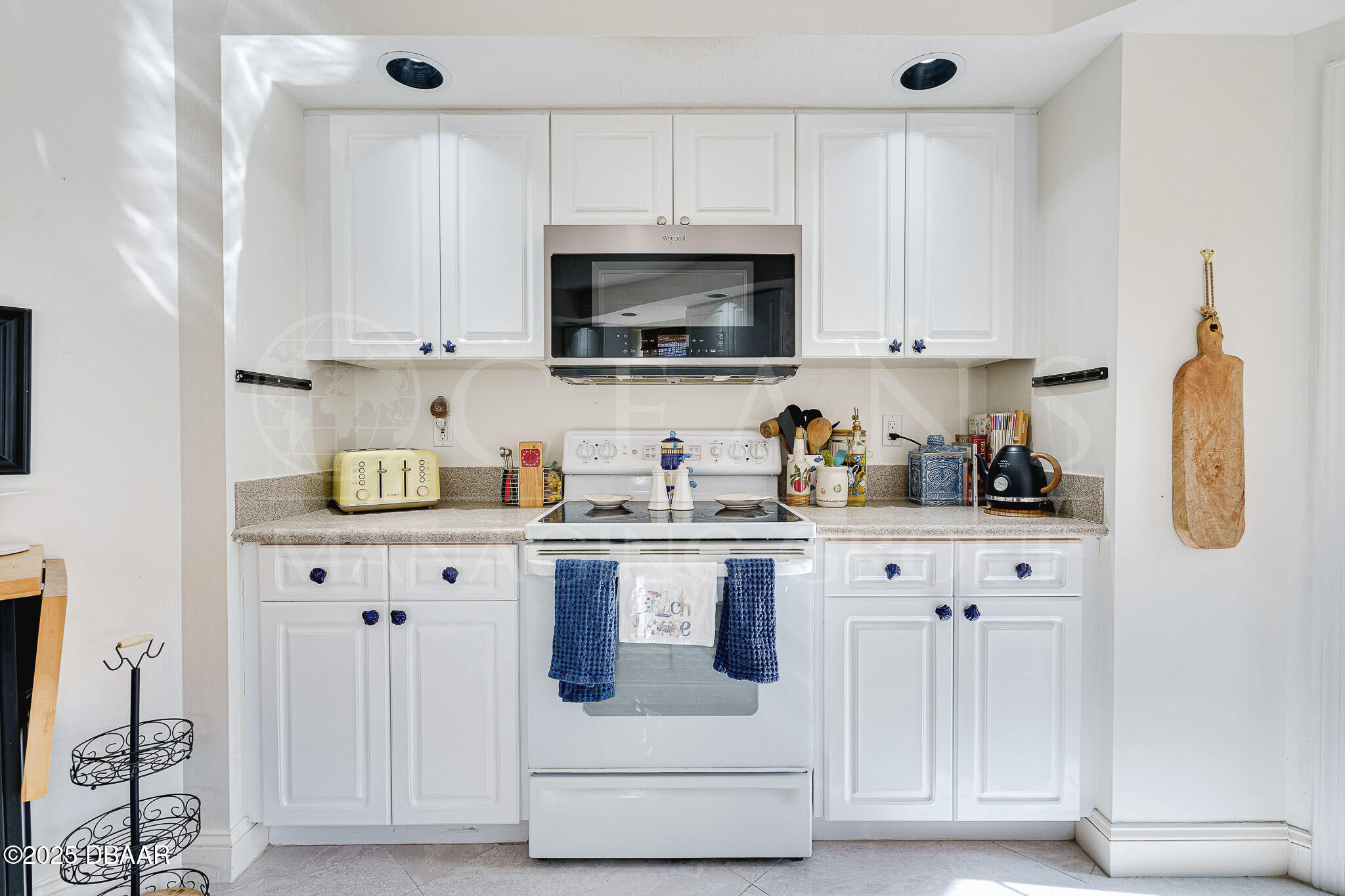 4650 Links Village Drive, Unit C303 Ponce Inlet, FL 32127 - Photo 11 of 67 a kitchen with white cabinets and stainless steel appliances