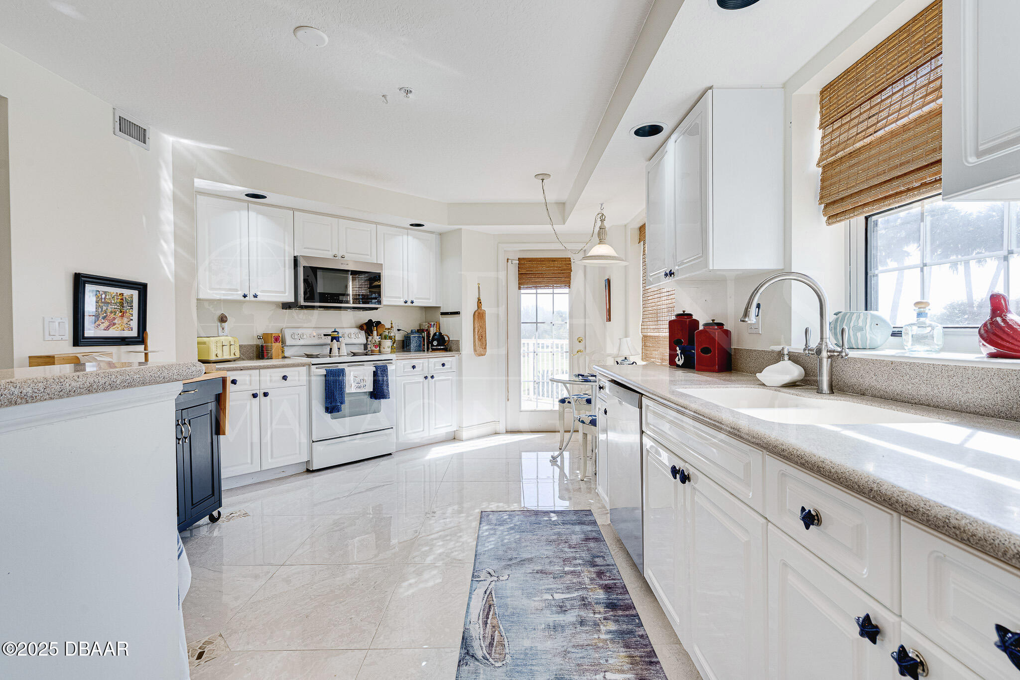4650 Links Village Drive, Unit C303 Ponce Inlet, FL 32127 - Photo 10 of 67 a kitchen with kitchen island granite countertop a sink appliances cabinets and a counter top space