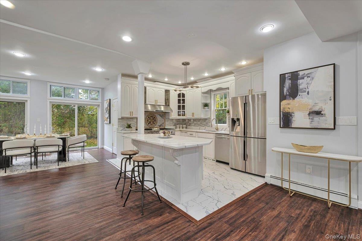 193 Nelson Road Scarsdale, NY 10583 - Photo 8 of 37 a kitchen with stainless steel appliances a refrigerator a stove a sink dishwasher a dining table and chairs with wooden floor