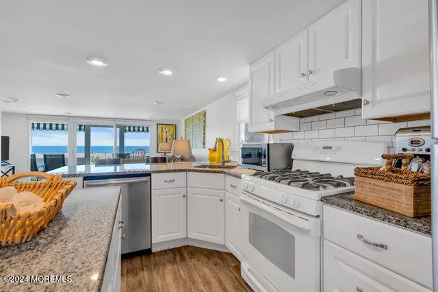 a kitchen with stainless steel appliances granite countertop a stove and white cabinets