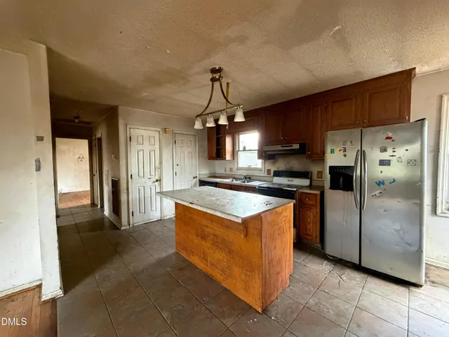 a kitchen with stainless steel appliances granite countertop a refrigerator a sink dishwasher a stove and a refrigerator